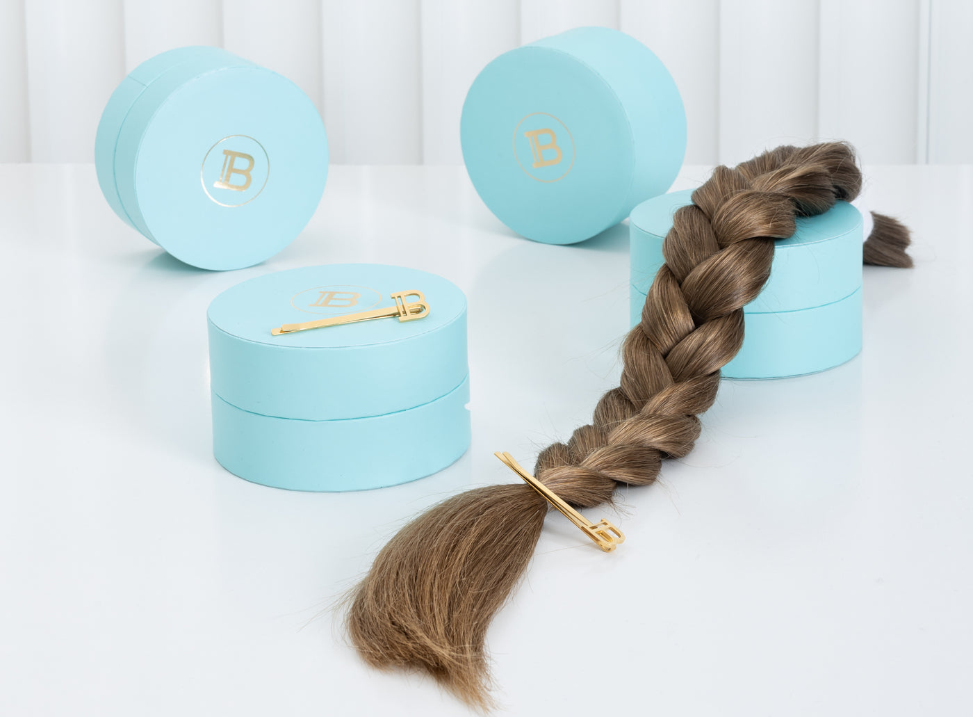 Brunette braided ponytail with hairpin in sitting on top of Balmain hair products. Shot in studio.